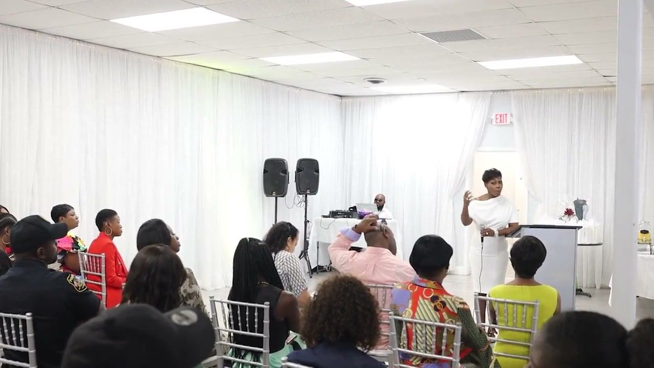A speaker addressing a seated audience in a draped event room