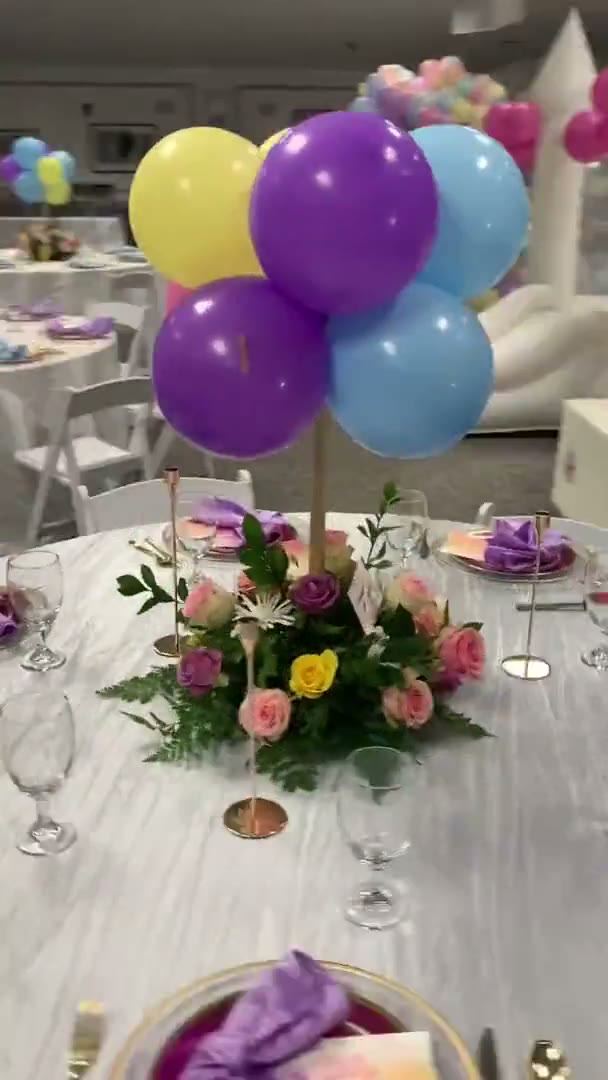 A pastel balloon and floral centrepiece on a dressed banquet table