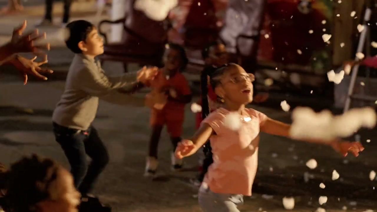 Children playing in artificial snow at an outdoor community Christmas festival