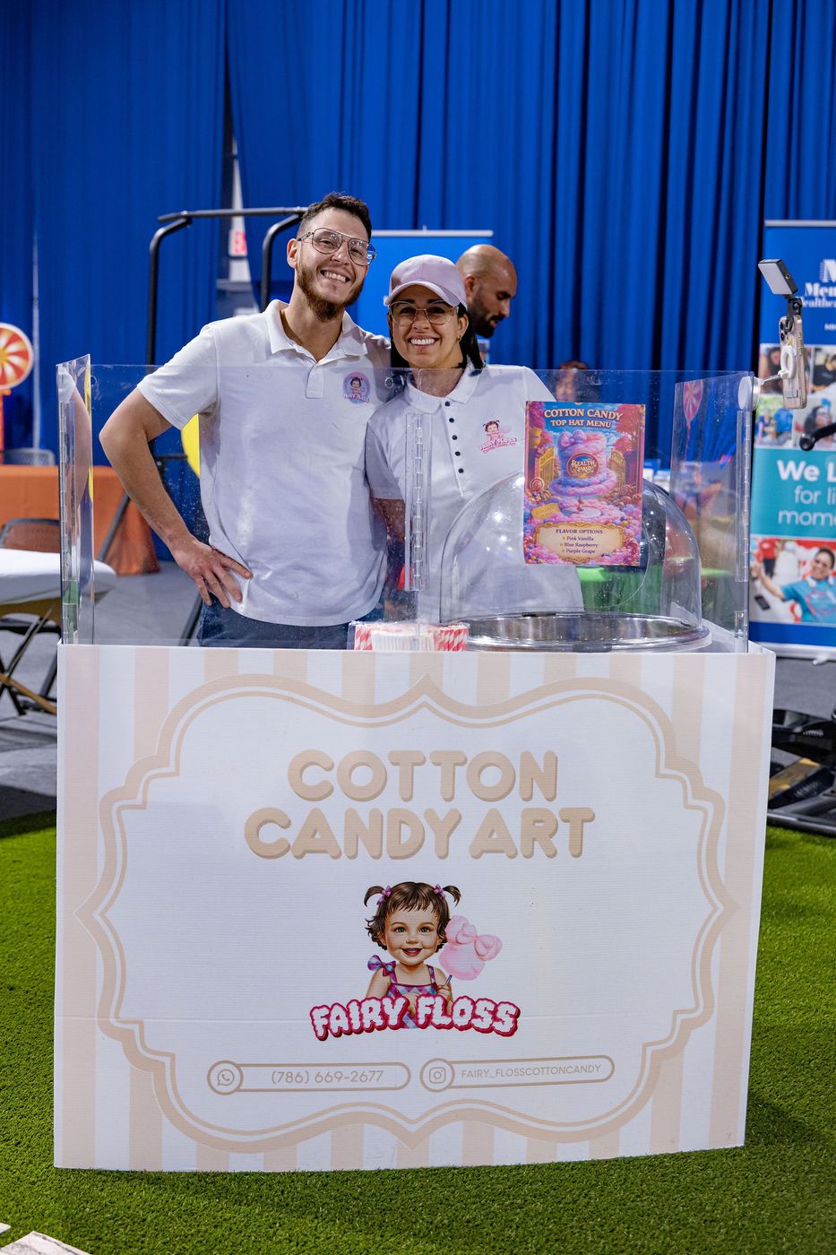 Two vendors photographed at their cotton candy stand during a family event