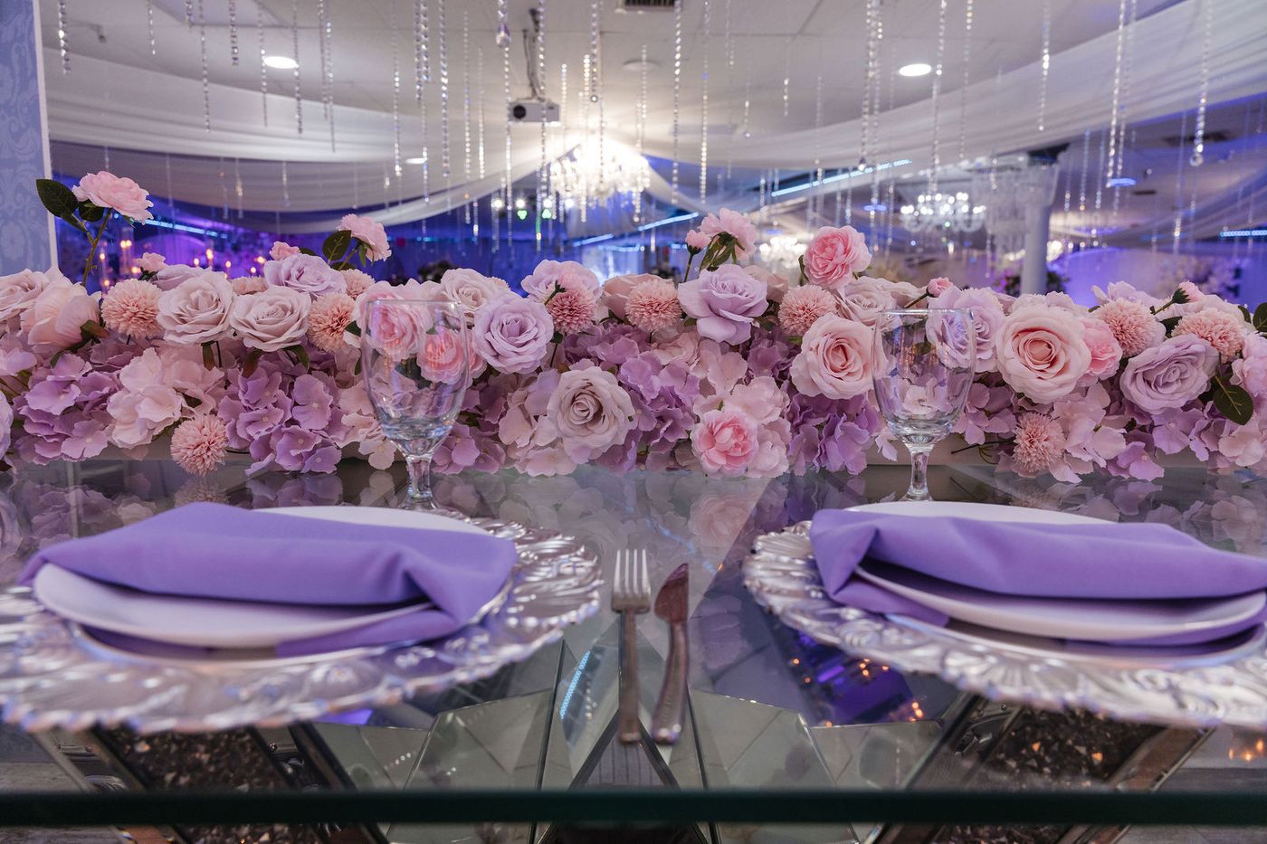 A long runner of blush and lilac roses down a mirrored sweet sixteen table