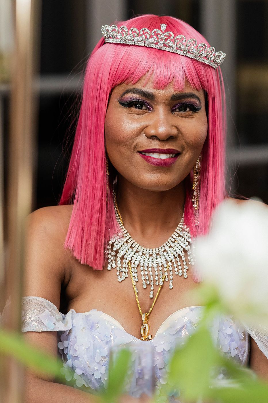 A guest in a jewelled gown and pink wig at a themed ball
