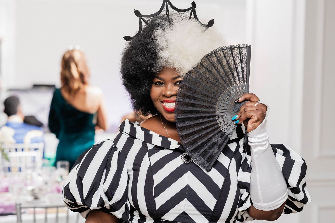 A guest in a monochrome striped gown with a black lace fan