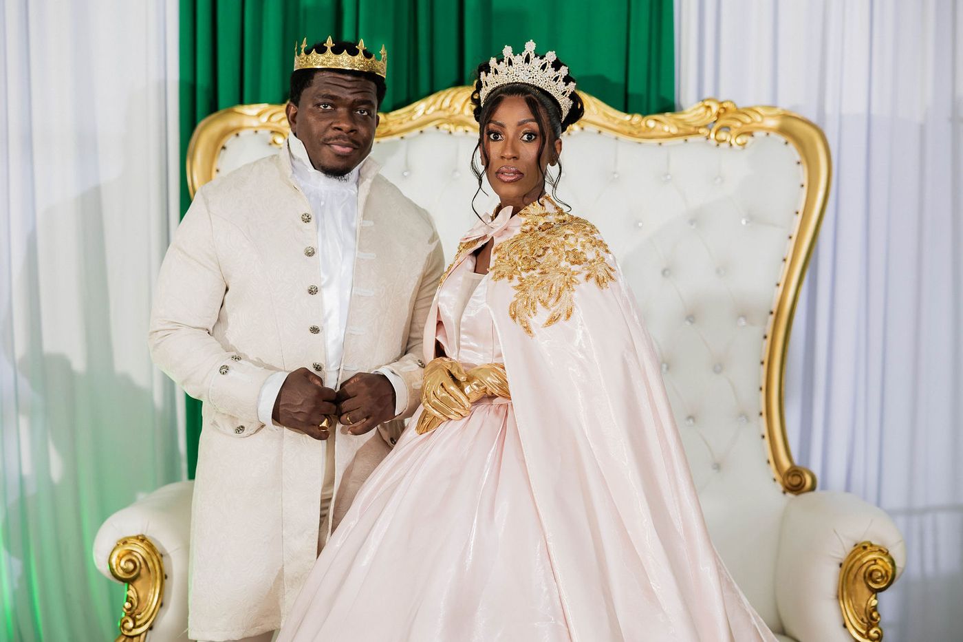 The host couple photographed on the gilded thrones of a costume ball