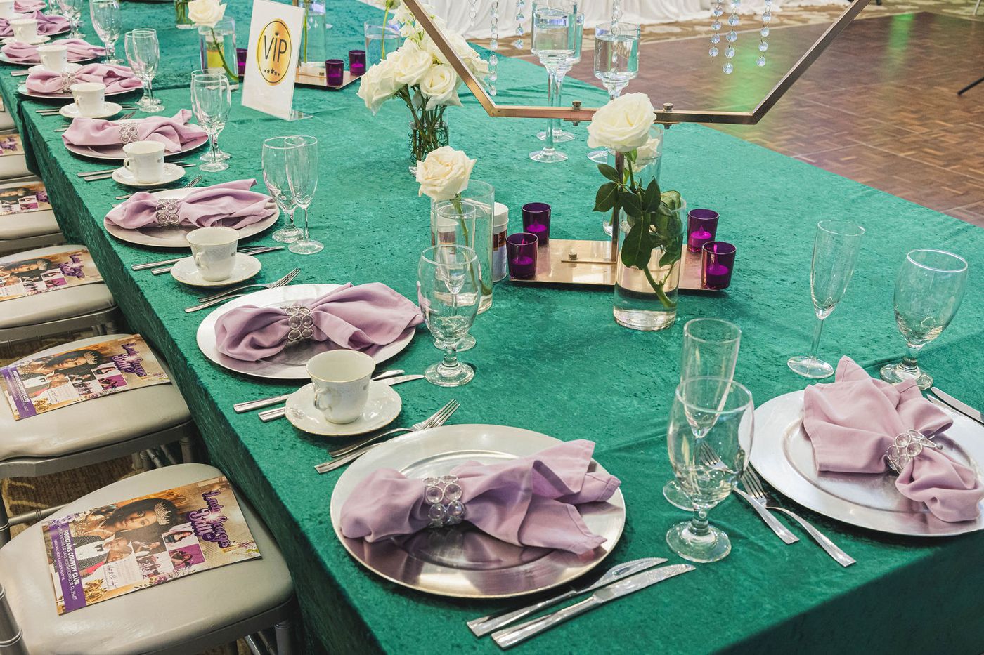 An emerald tablescape laid with china, pink napkins and crystal
