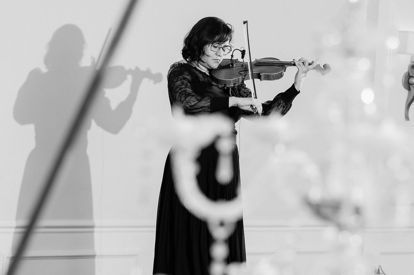 A black and white frame of the violinist at a Regency themed ball