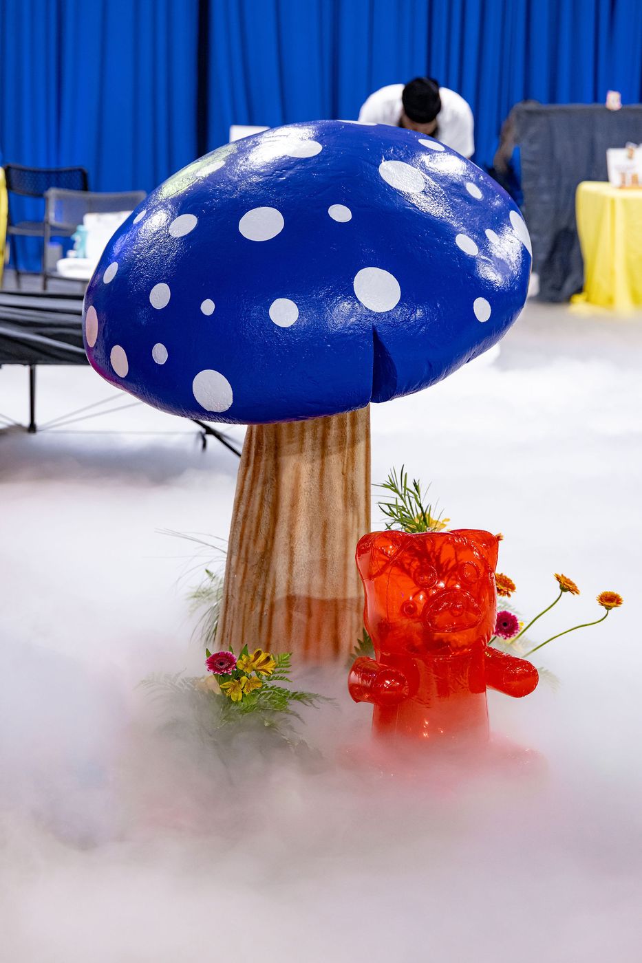 A giant blue toadstool rising out of low fog at an immersive event build