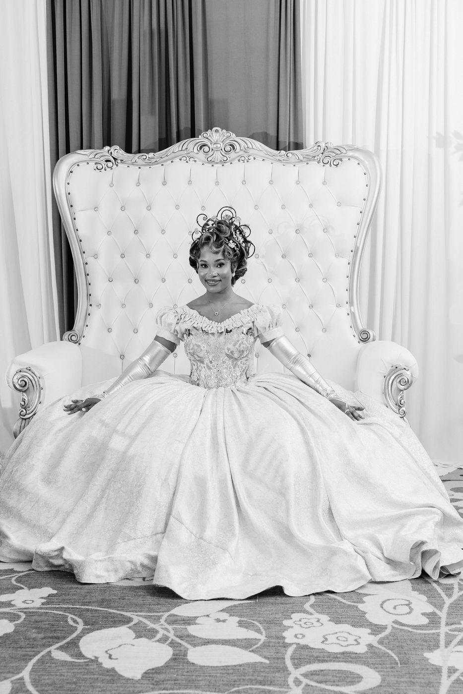 A black and white throne portrait of a guest in a full court gown