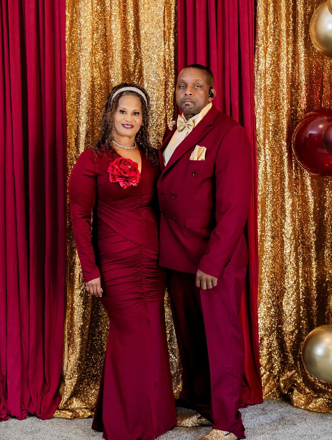 A couple photographed at the anniversary backdrop in burgundy and gold