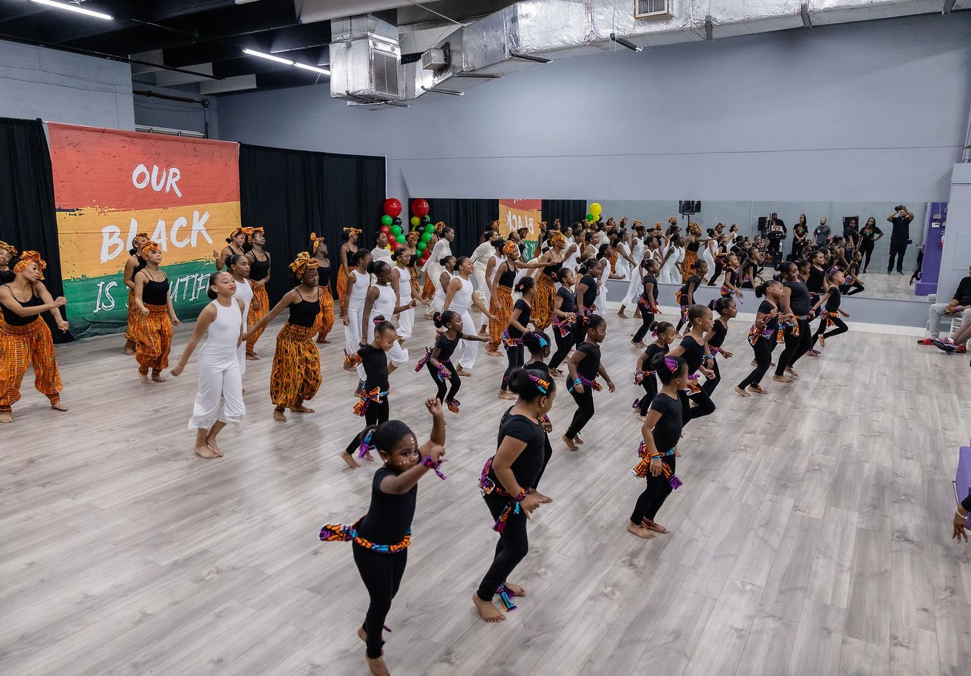 A wide view of a packed dance studio showcase with the whole cast on the floor