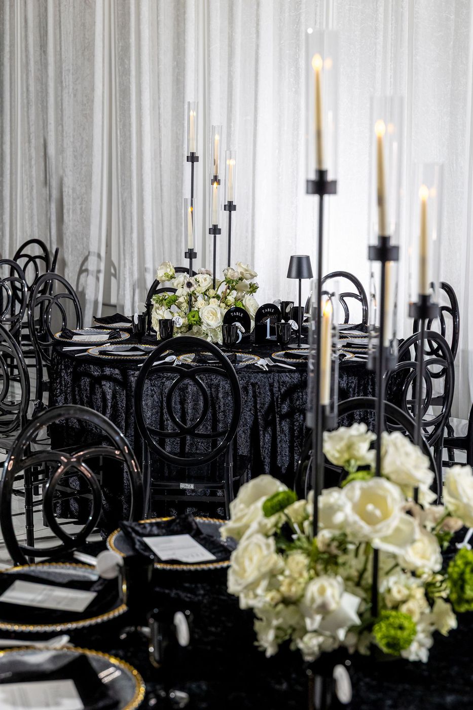 Black taper candles and white roses on a black velvet banquet table