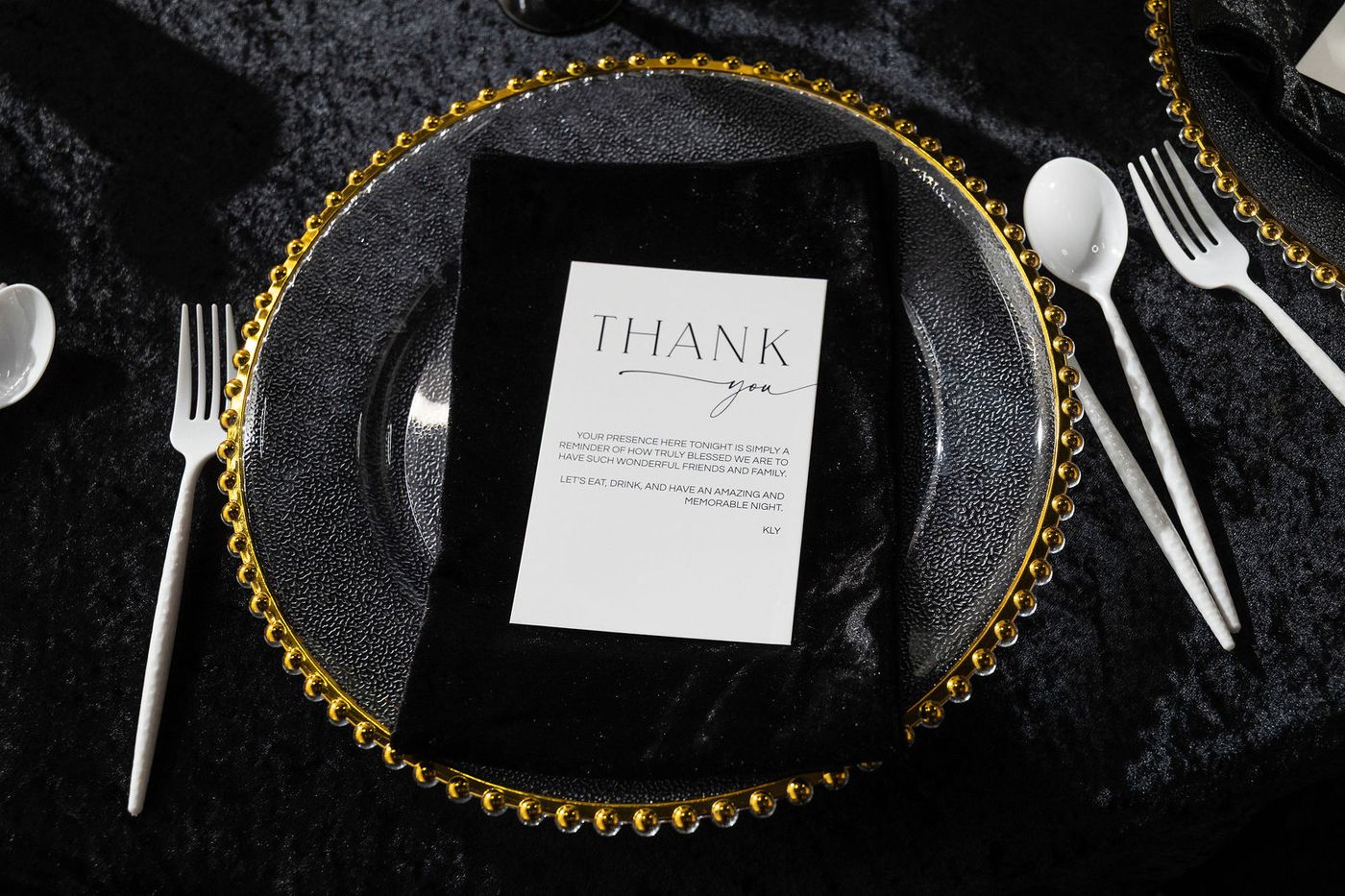 A place setting on a beaded gold charger over black velvet