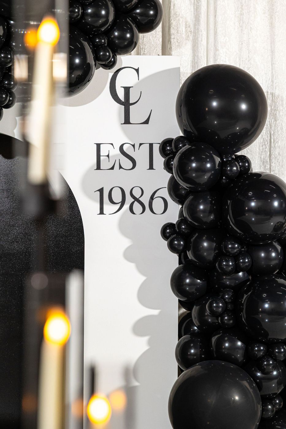 A monogrammed arch and black balloon garland for a 40th birthday