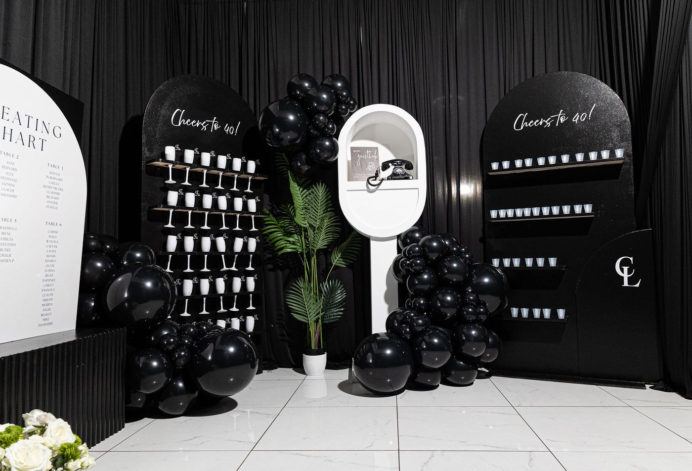 A champagne wall and black balloon installation at a milestone birthday