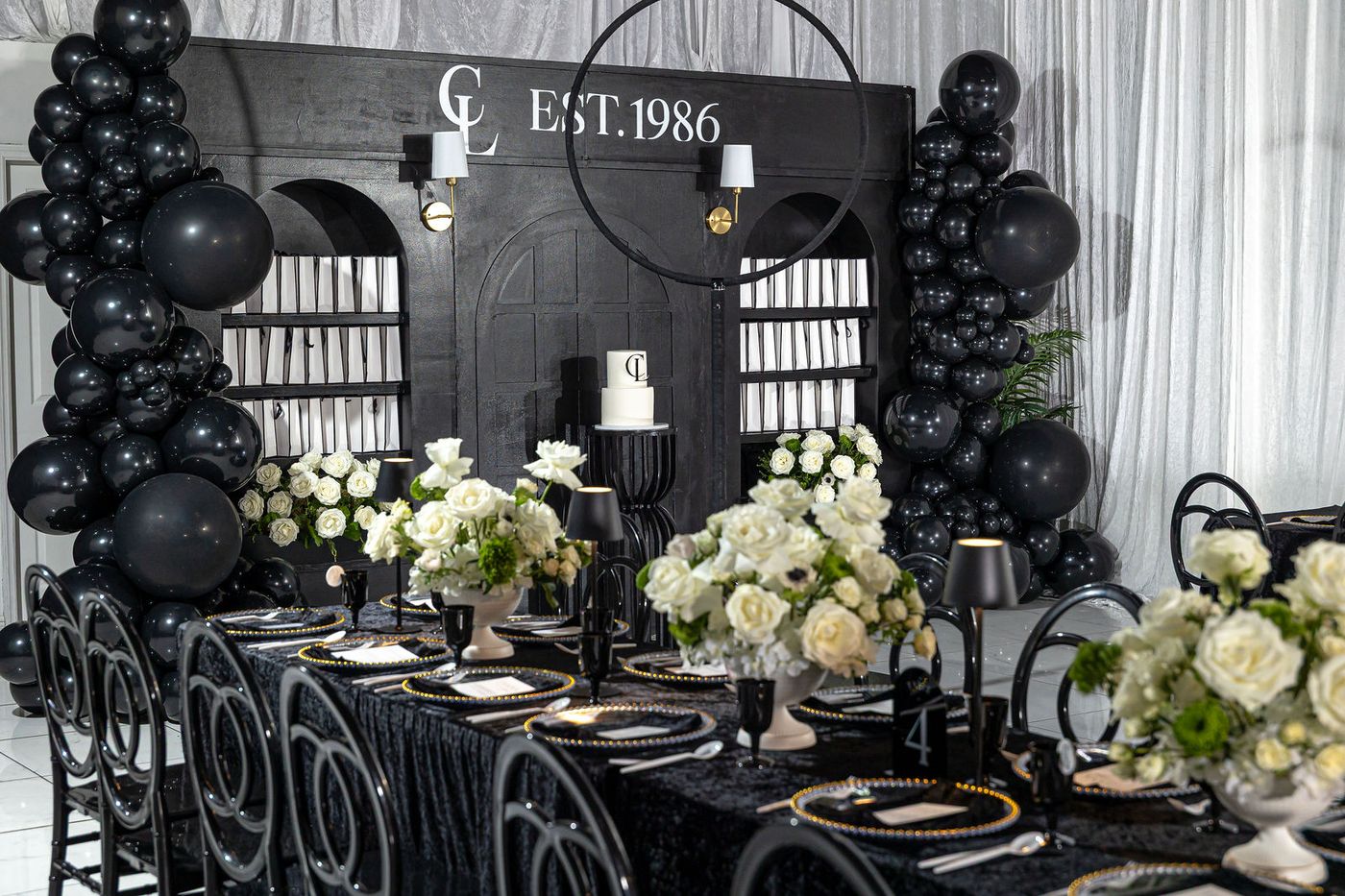 The head table of a black and white 40th birthday, laid with white roses