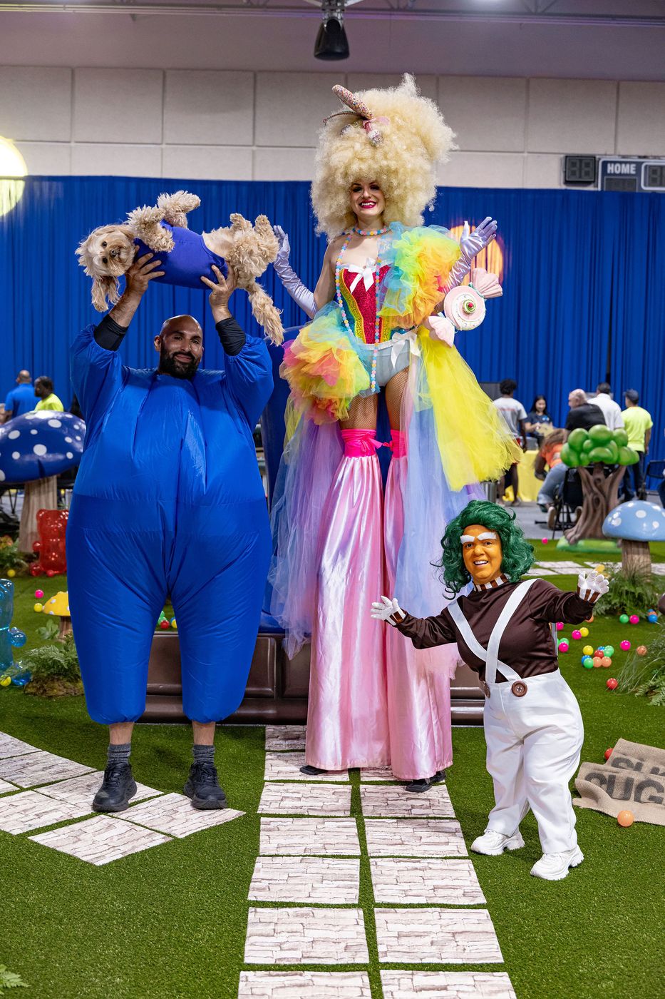 A stilt walker in rainbow tulle performing beside costumed characters