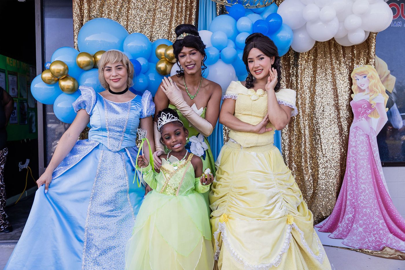 Costumed princess characters photographed with a child at a community kids' prom