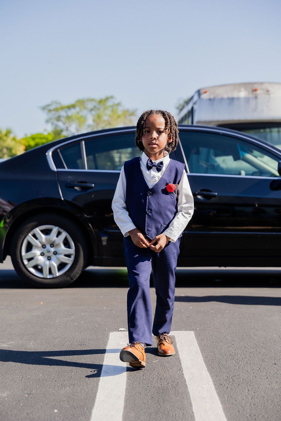 A boy in a waistcoat and bow tie arriving at a community kids' prom