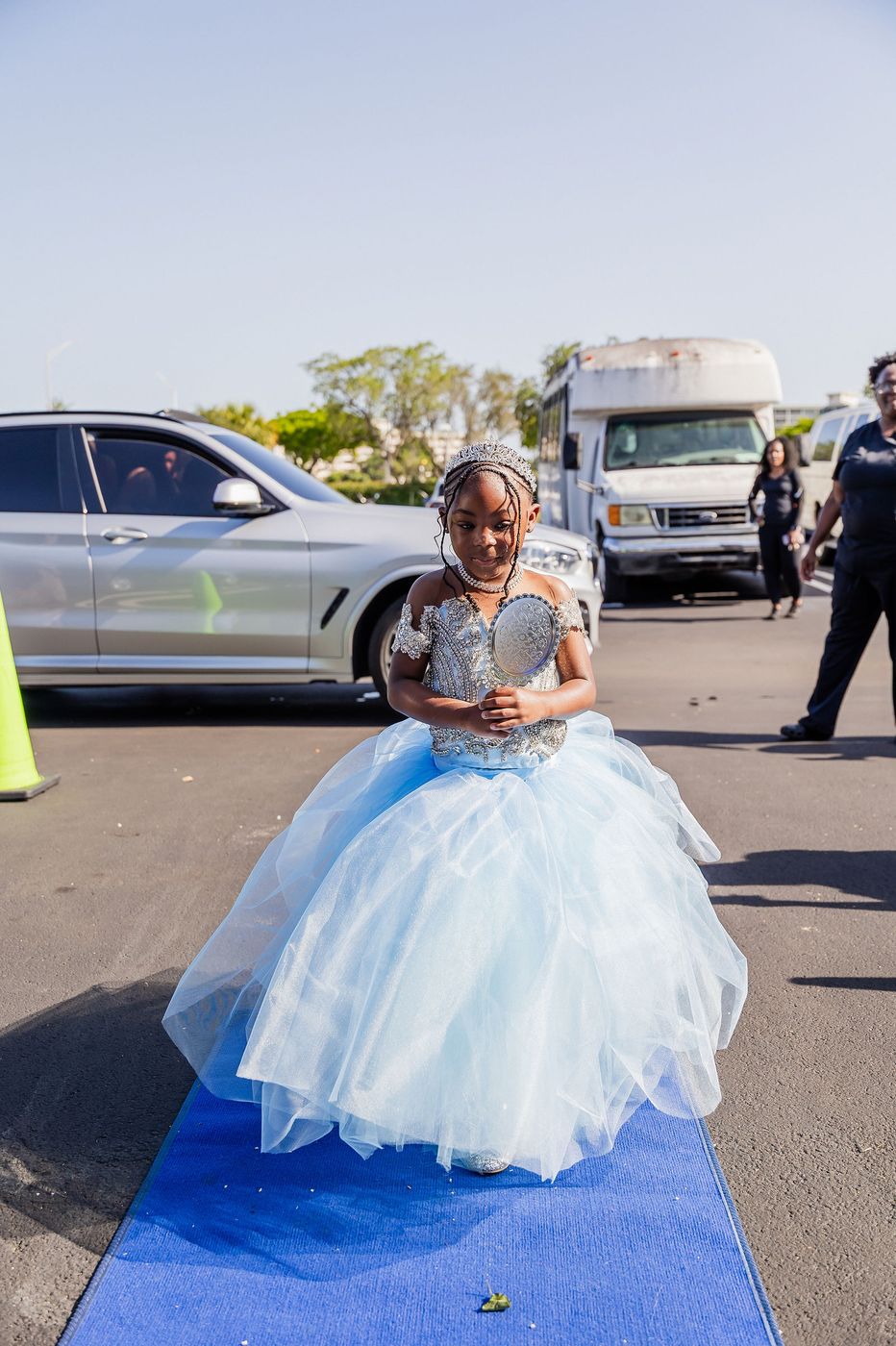 A child in a blue ball gown on the blue carpet at a kids' prom night