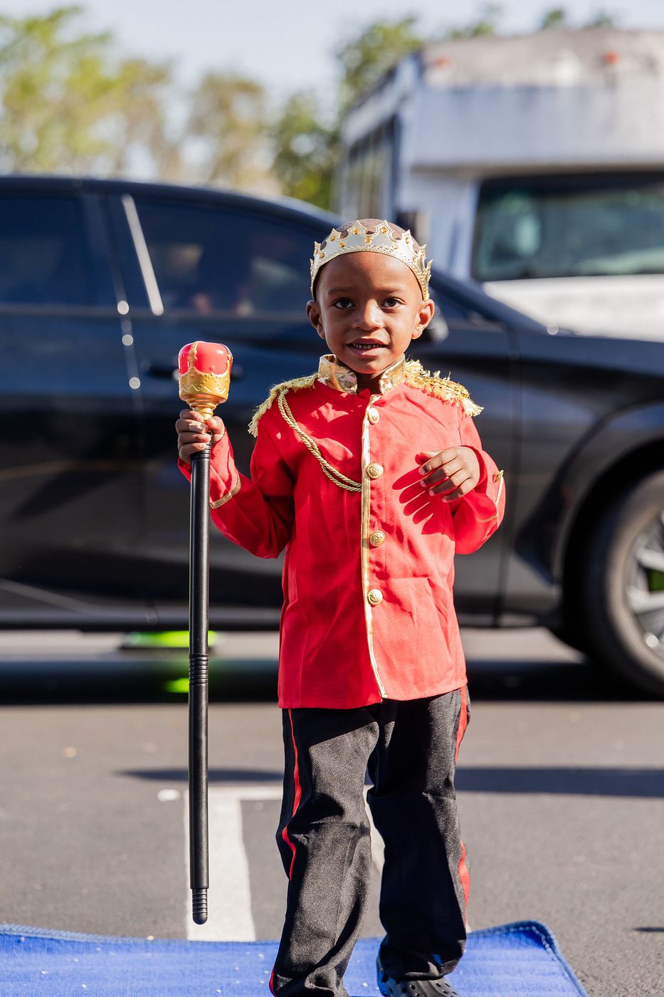 A child in a red cape and crown on the blue carpet