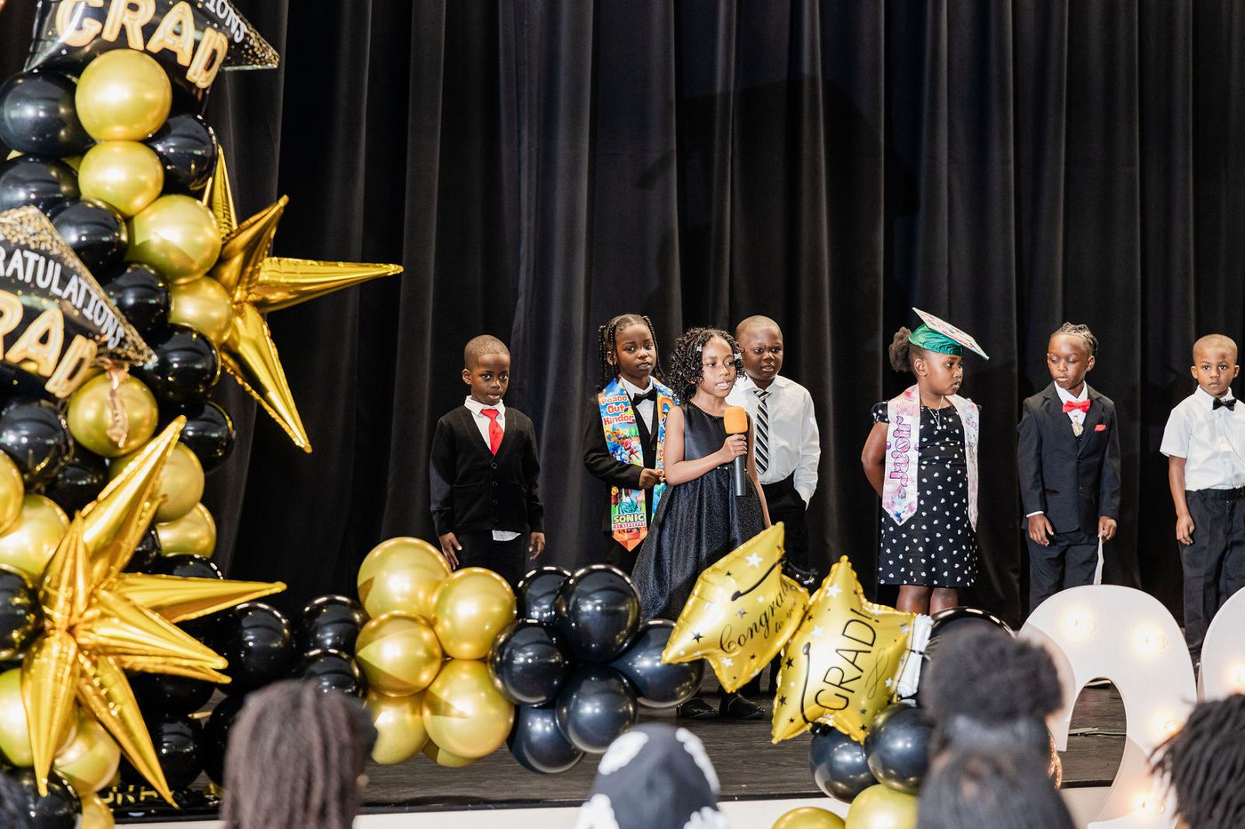Graduating children lined up on stage in cap and gown