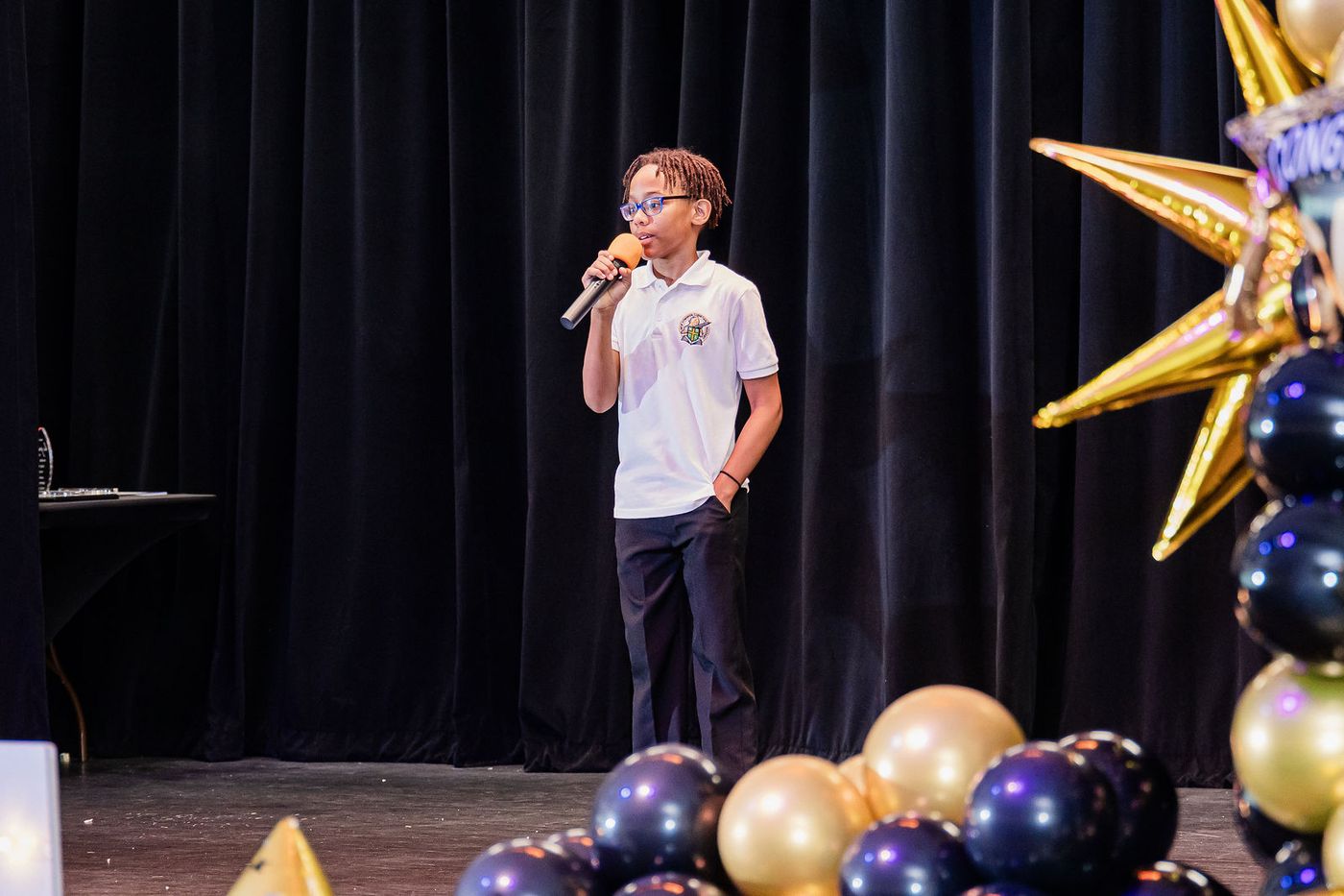 A young graduate singing into a microphone on stage