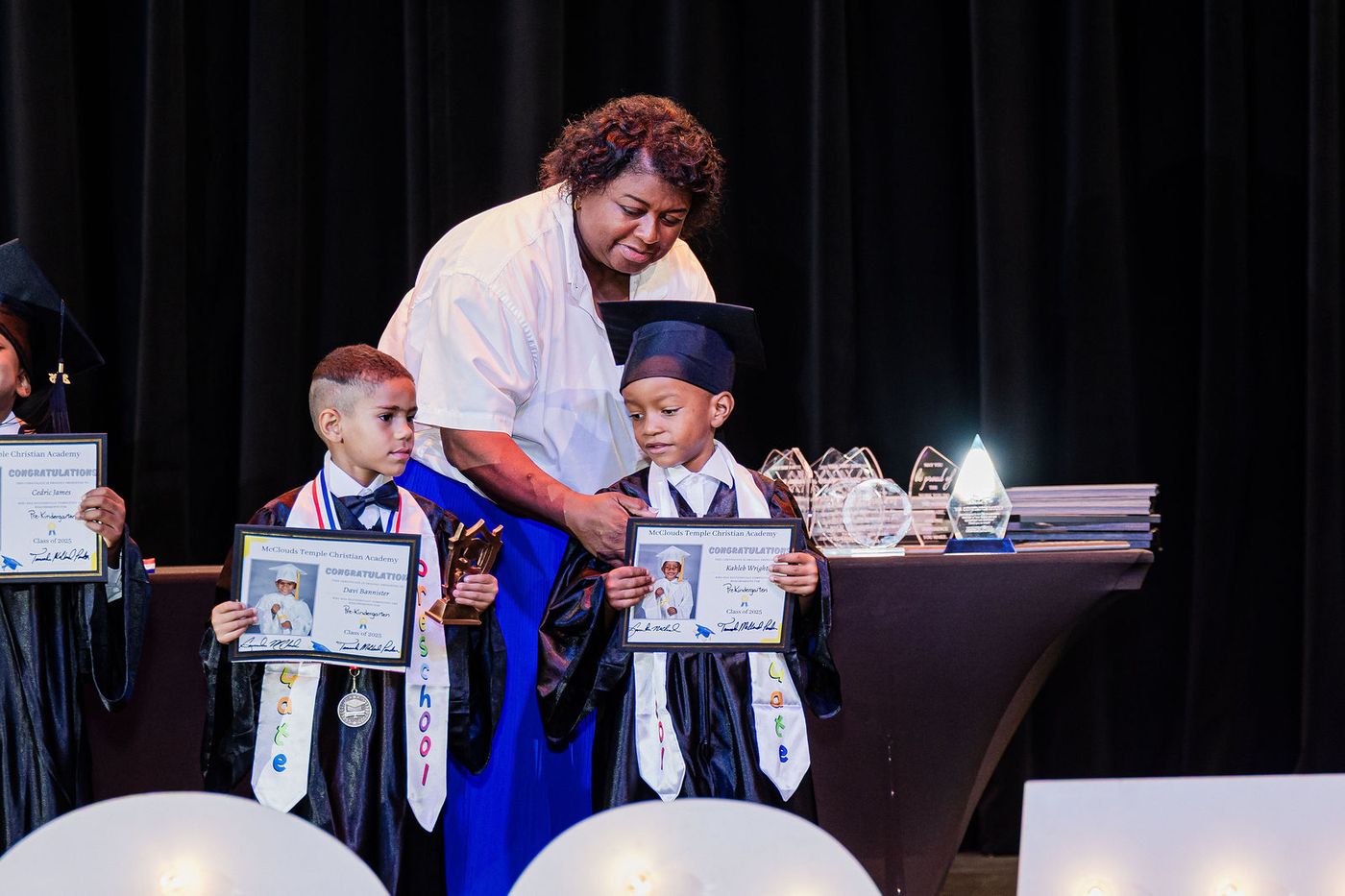 A young graduate holding his certificate beside the awards table