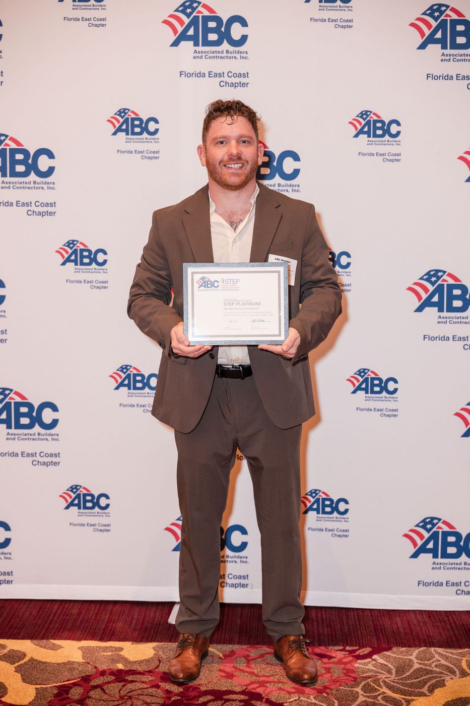 A member photographed with his certificate at the sponsor backdrop