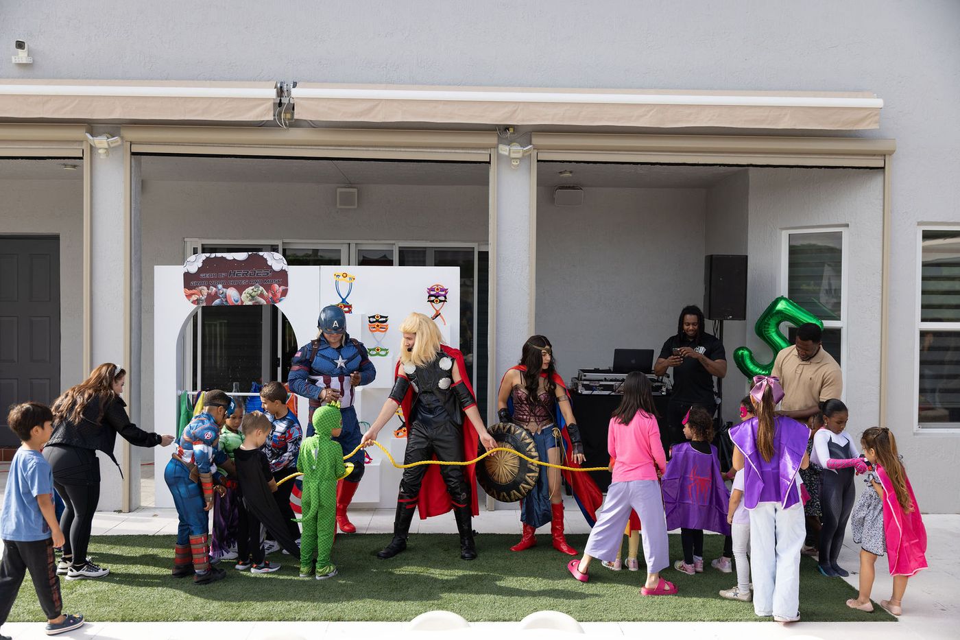 Children in superhero costume playing on the lawn at a themed birthday party