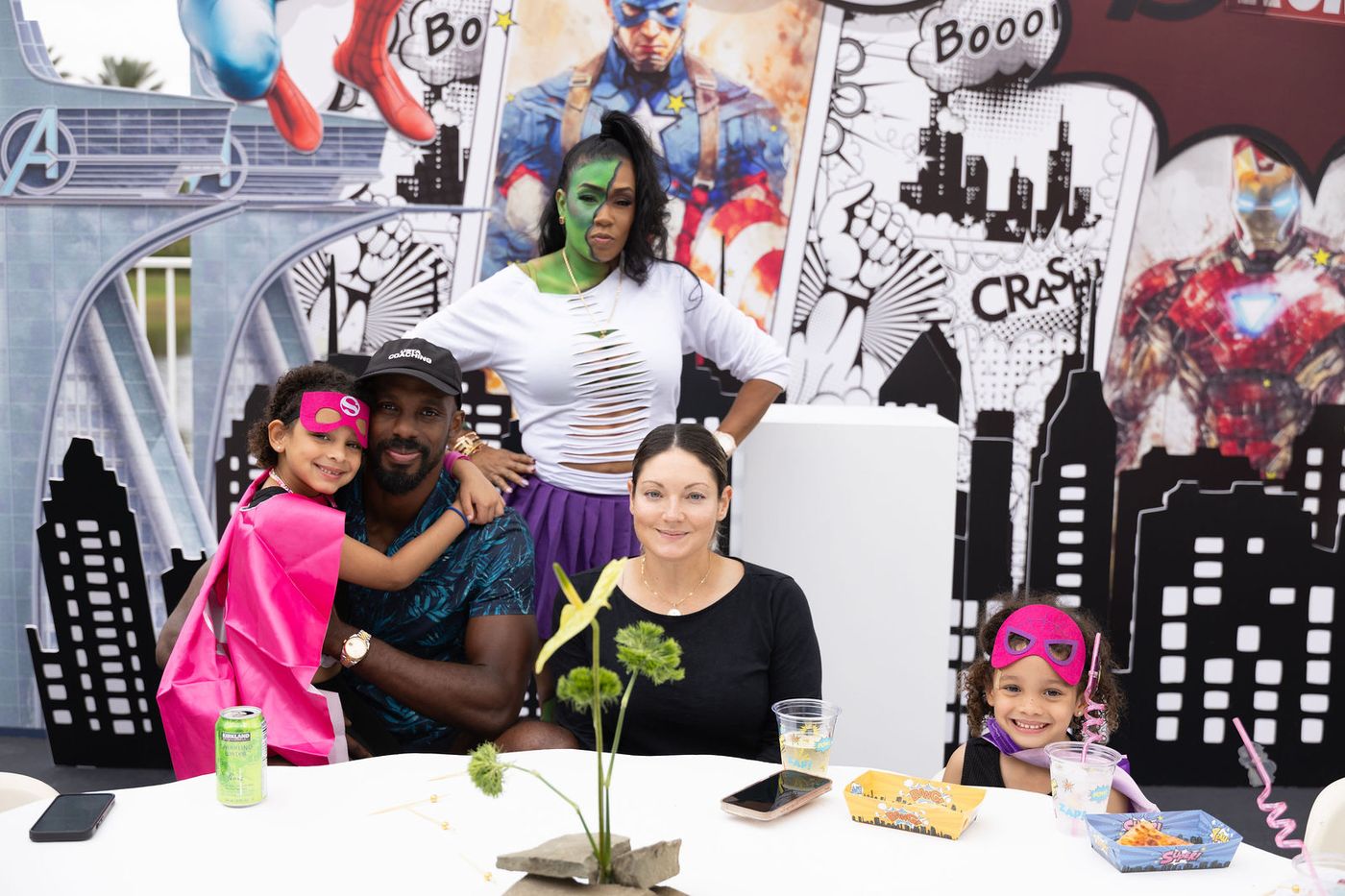 A family photographed at the comic-book backdrop of a children's birthday
