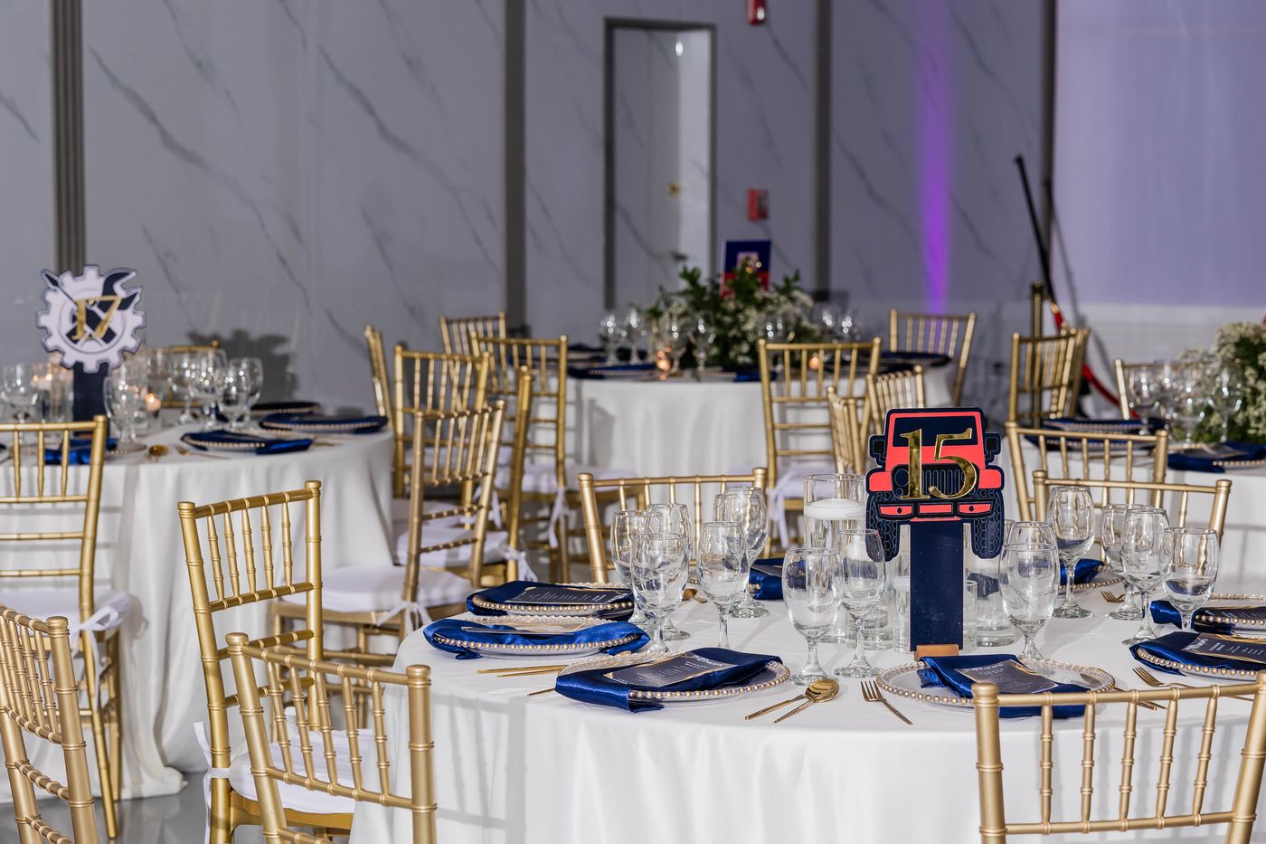 A navy and gold tablescape laid with chiavari chairs for a 70th birthday gala