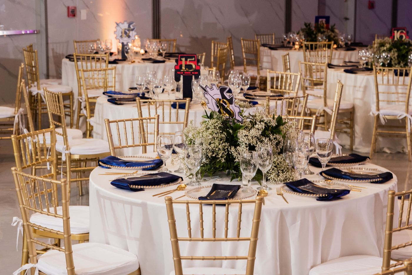 A long banquet table beneath a navy and gold balloon ceiling