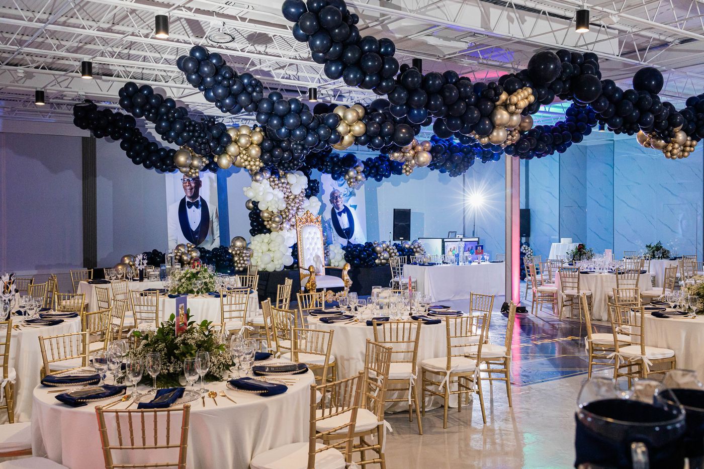 A 70th birthday ballroom, portrait banners behind the head table