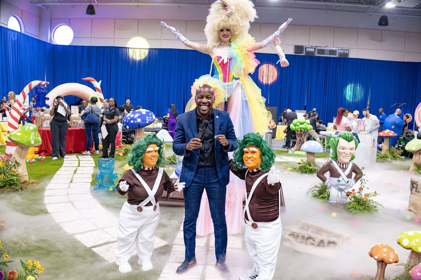 A stilt walker with arms outstretched over the floor of a themed event