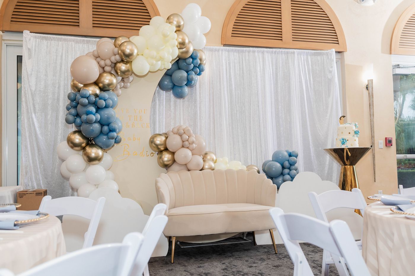 A blue and cream balloon arch with cloud cutouts at a baby shower