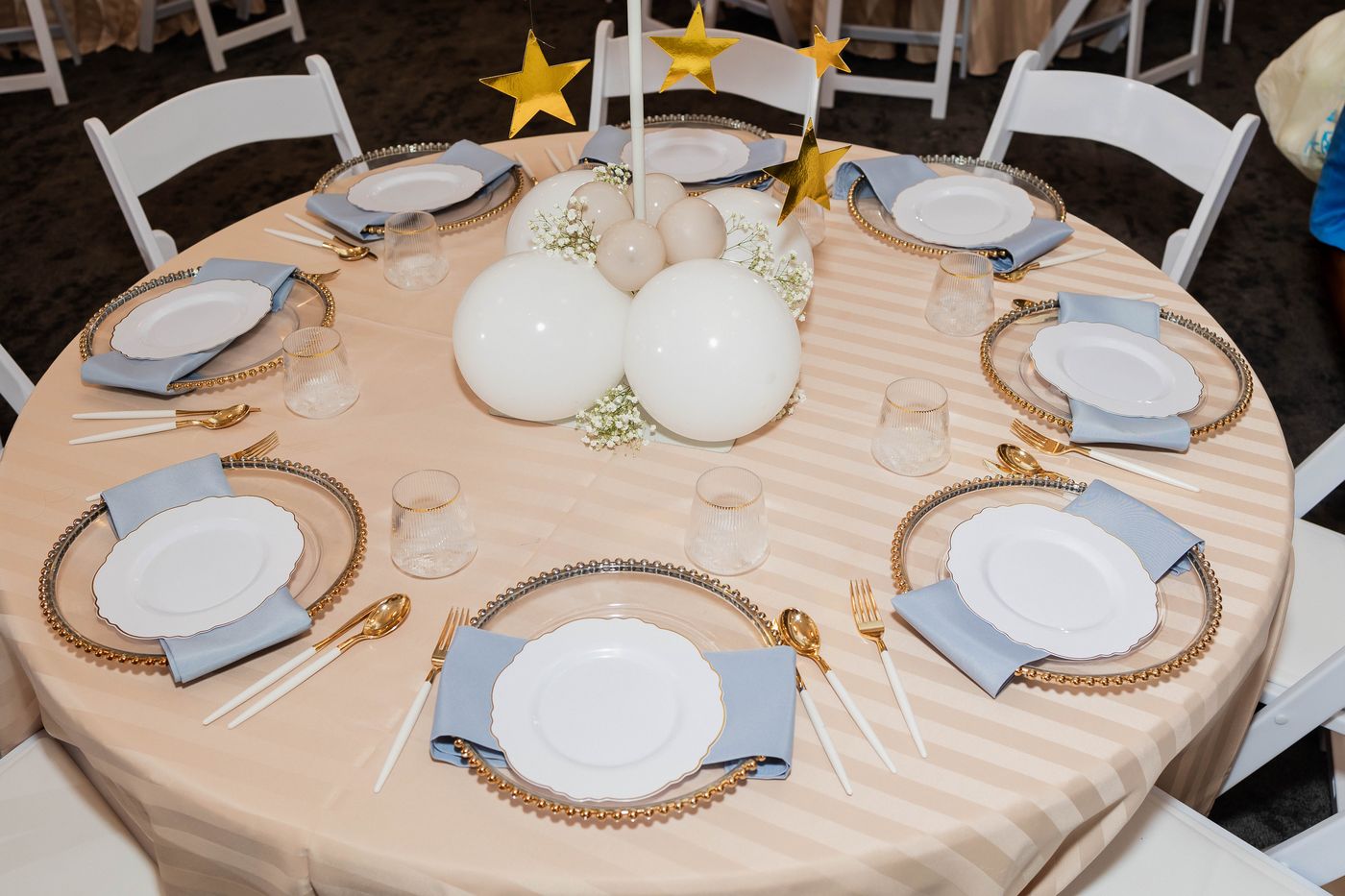 A place setting in blue and gold on a striped cloth