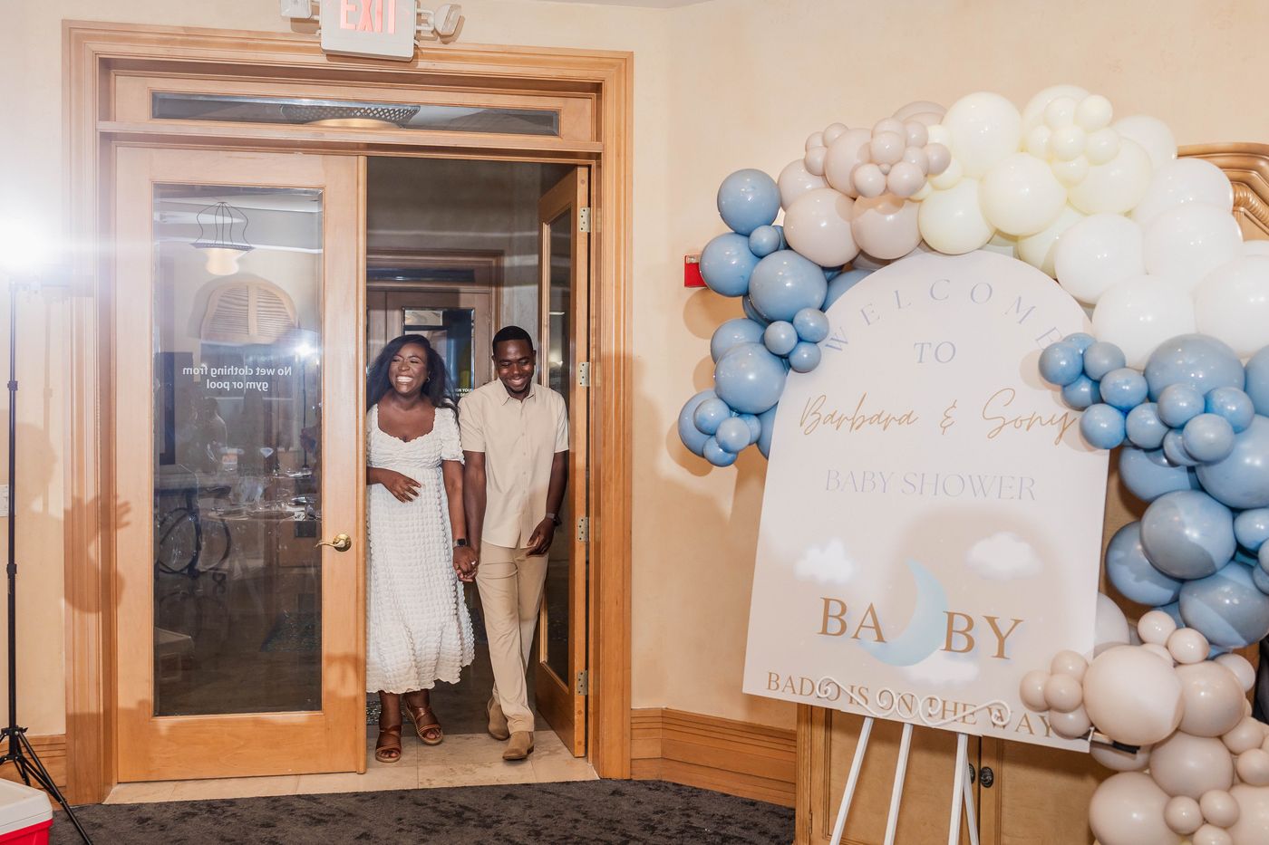The parents-to-be arriving at their baby shower backdrop