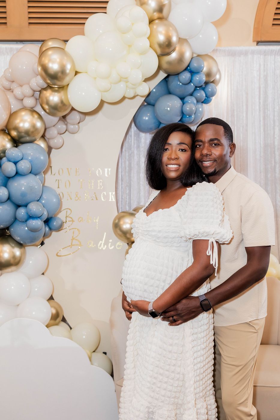 The parents-to-be at the baby shower backdrop