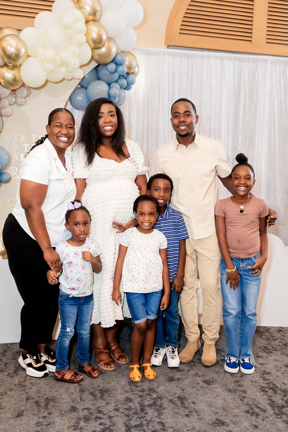 The family photographed together at a baby shower arch