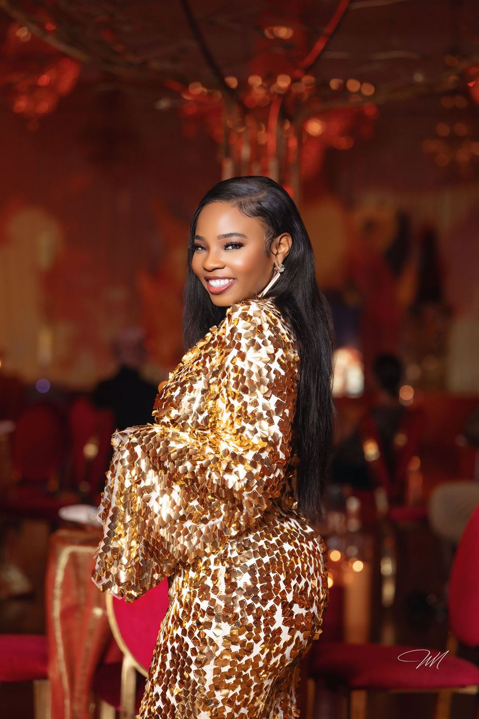 A guest in a gold sequinned gown on the portrait riser at a flame themed celebration