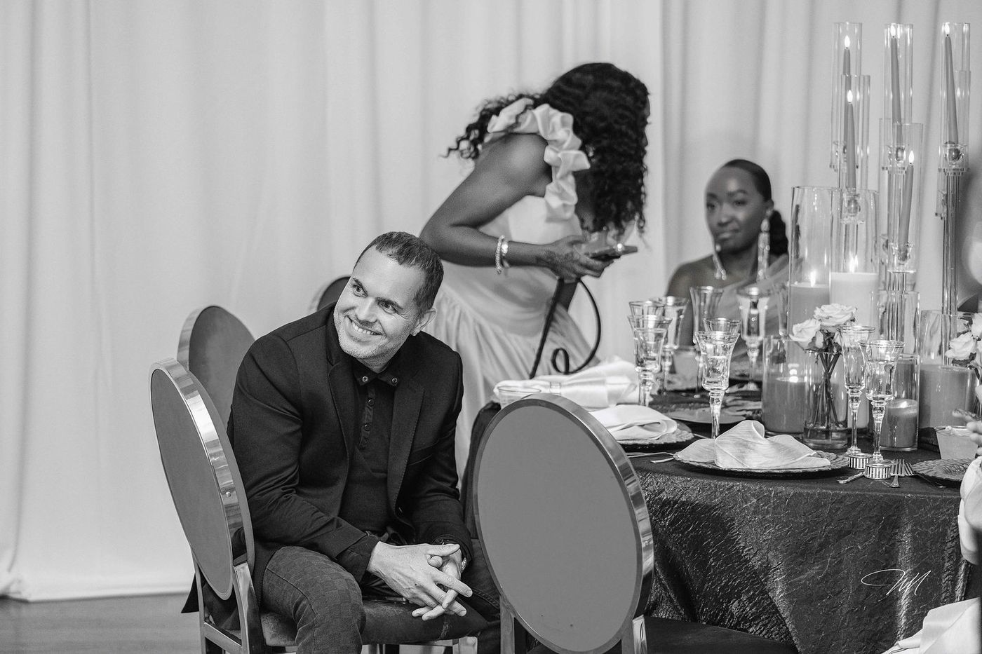 A black and white frame of guests at a candlelit table during the evening programme
