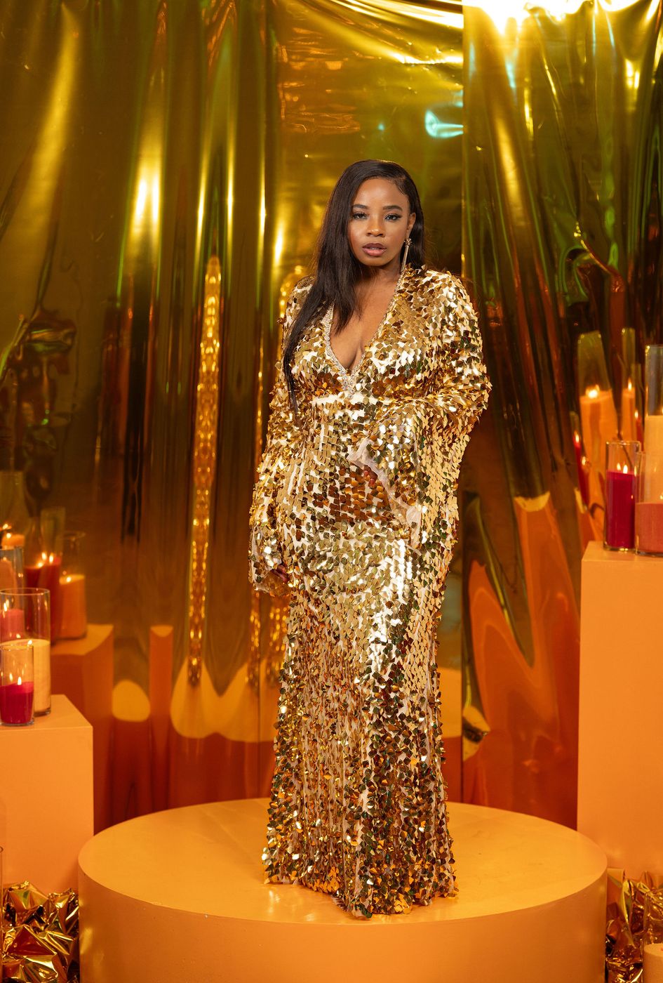 A guest in gold sequins and candlelight at a flame themed gala