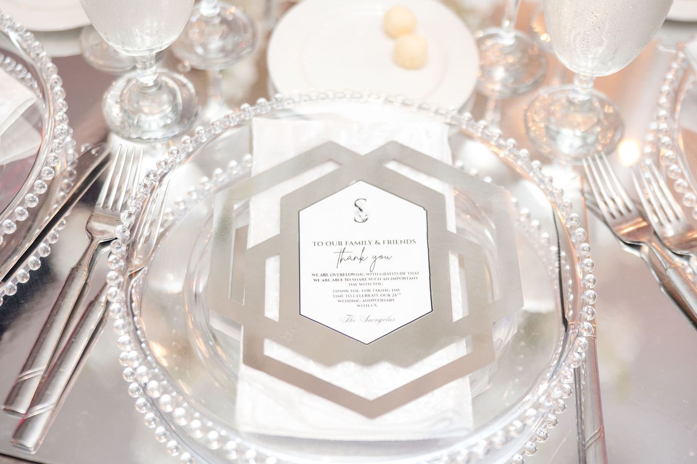 A place setting on a beaded charger with a printed menu card and polished silverware