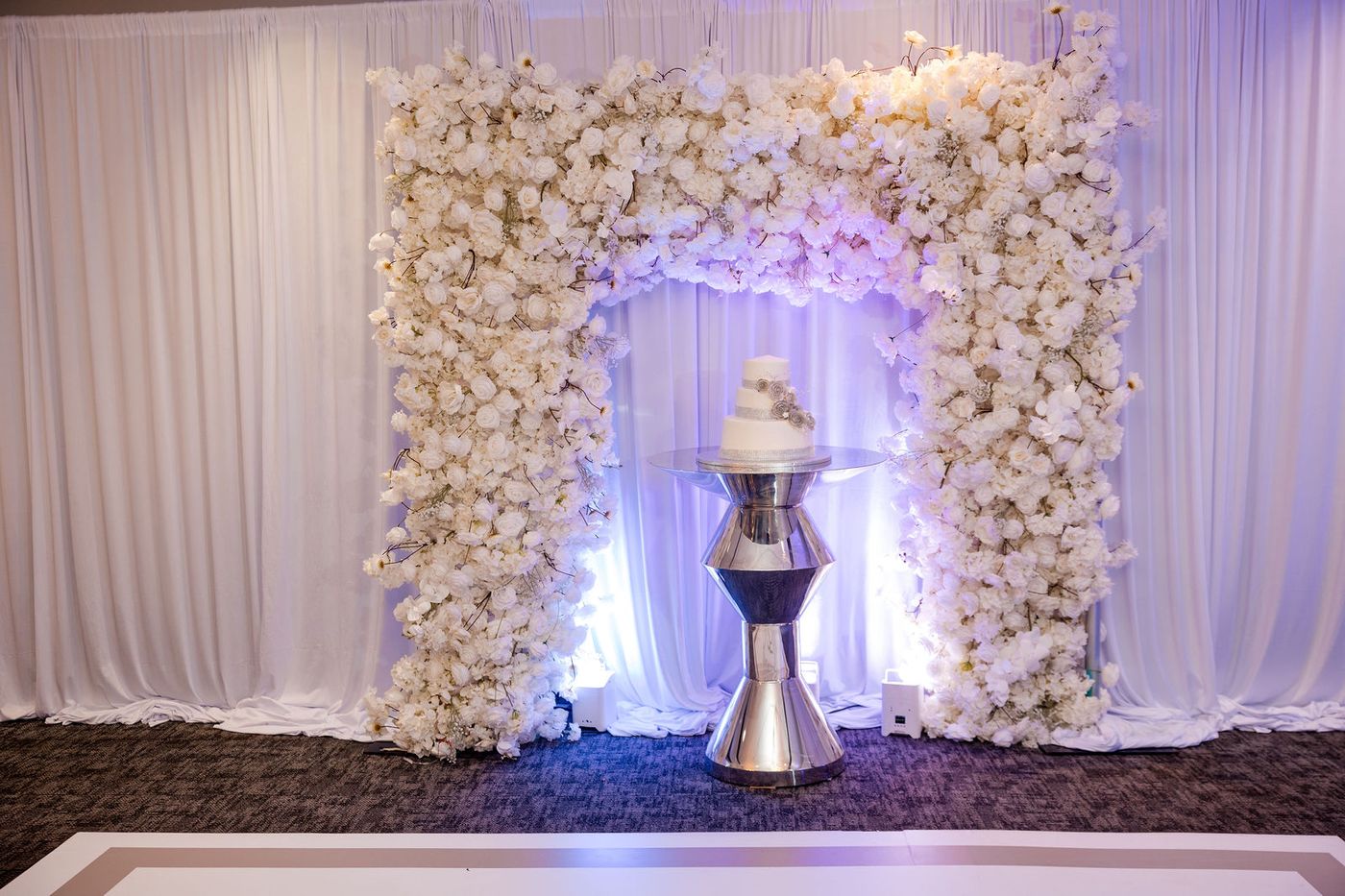 A wedding anniversary cake framed inside a white floral arch