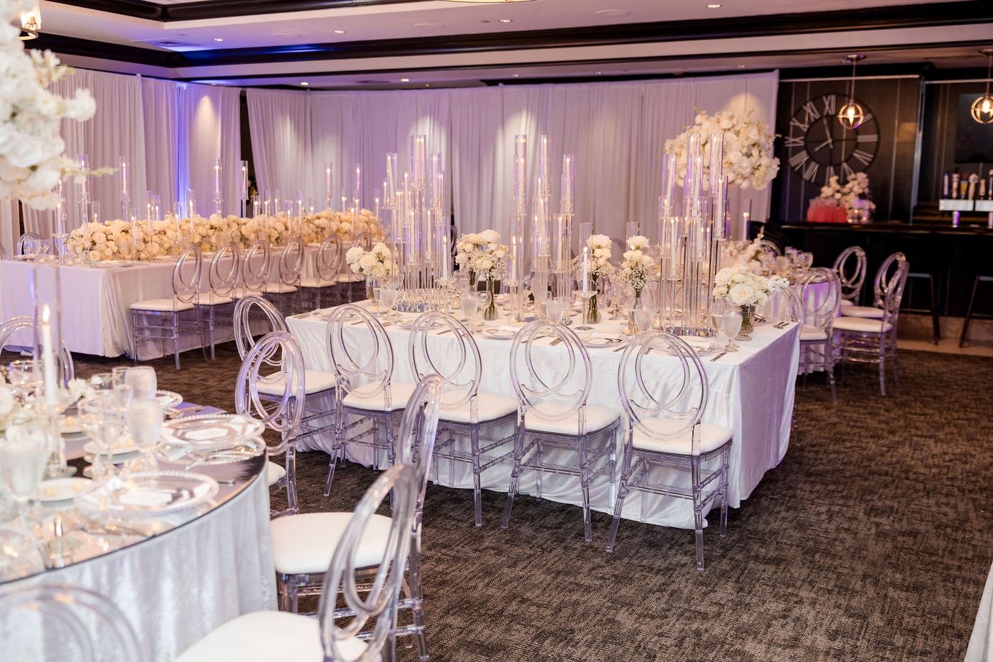 A hotel ballroom dressed entirely in white for a 25th anniversary gala, long tables under chandeliers