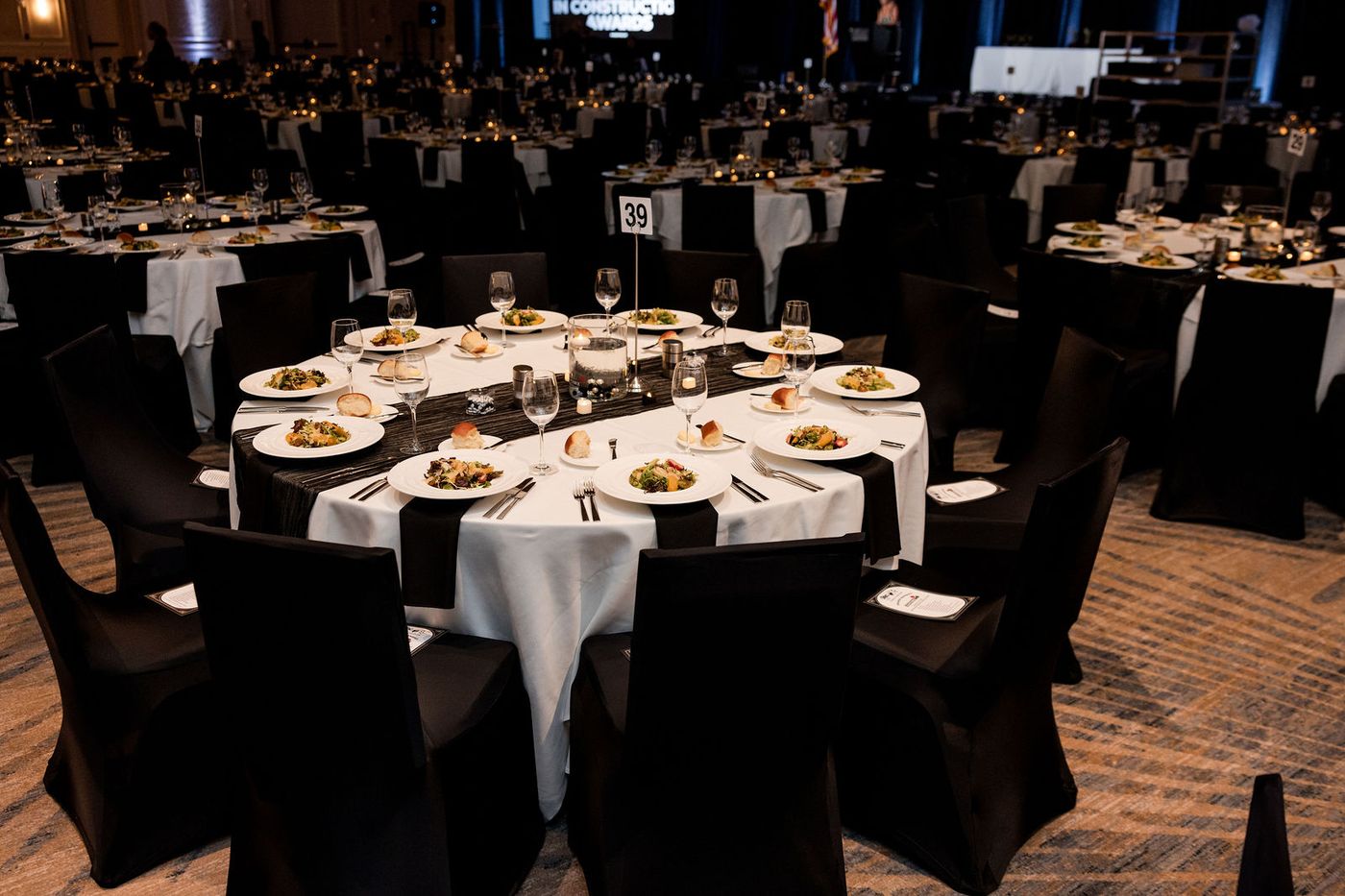 Banquet tables laid in black and white under warm ballroom light