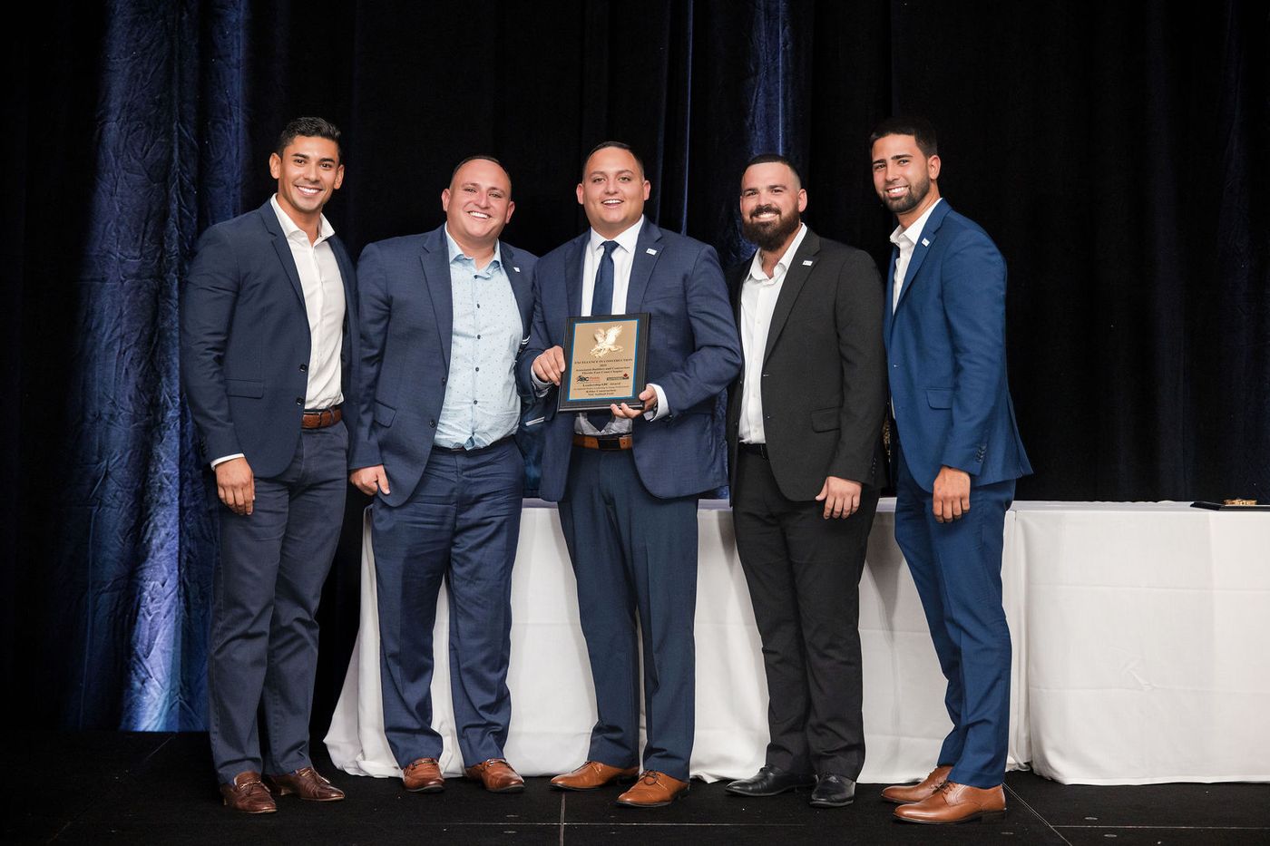 A team receiving an excellence award on stage at a South Florida banquet