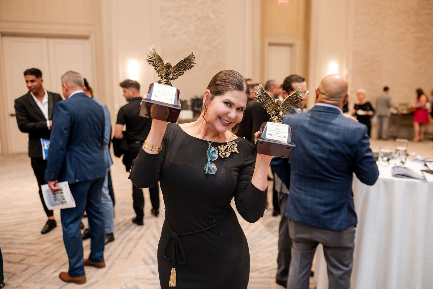 A guest holding her award aloft on the floor of an awards banquet